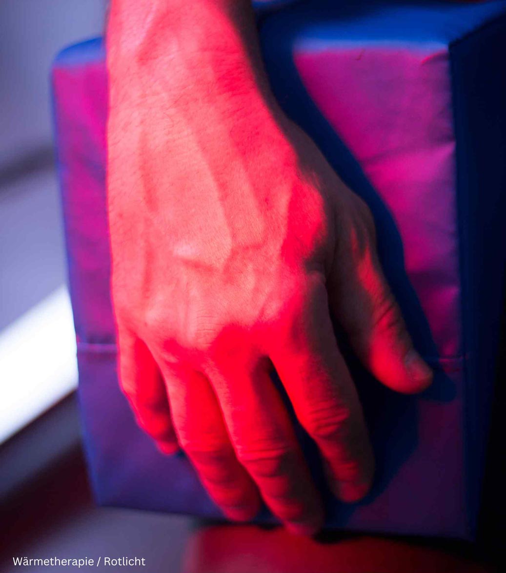 Eine Hand wird von einem Rotlichtstrahler angeleuchtet